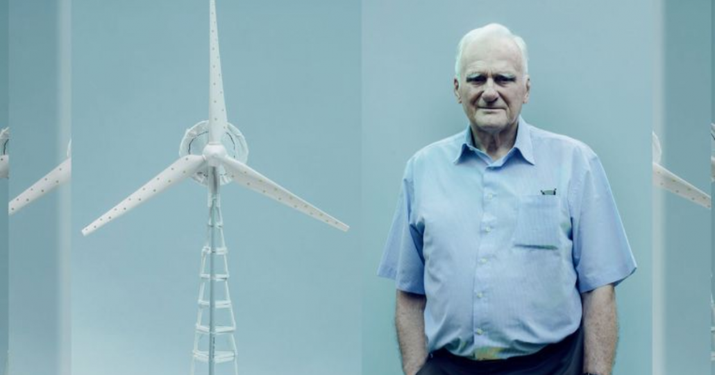 Foto do engenheiro aposentado ao lado do protótipo em escala reduzida de sua turbina eólica